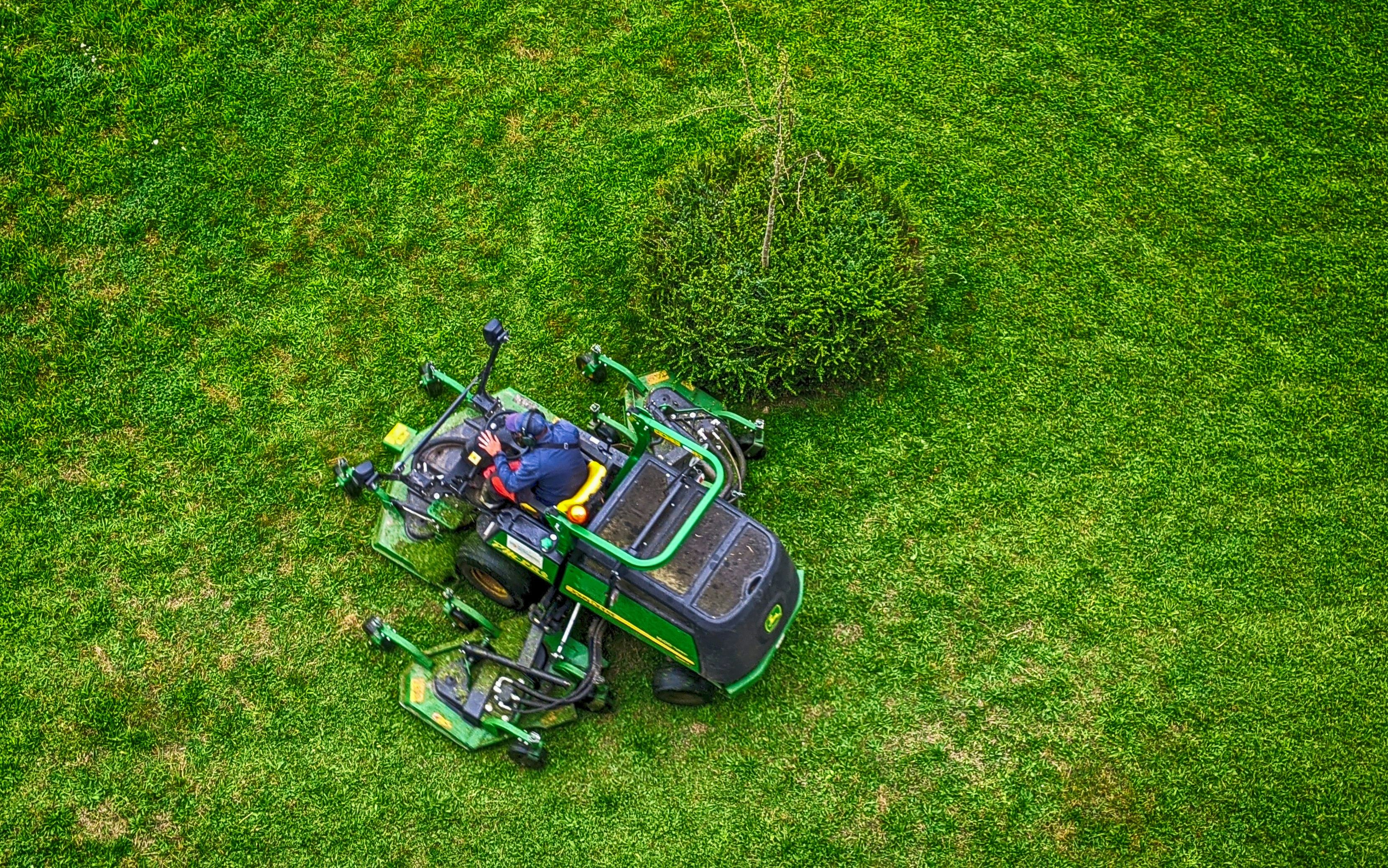 A high-end commercial lawn mower parked neatly on a vibrant green grass lawn in a residential neighborhood.